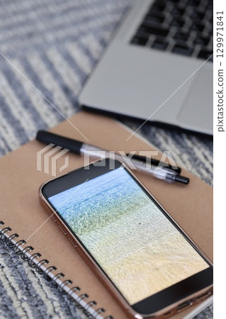 地毯上放置著一台筆記型電腦、一部智慧型手機和一些書寫工具 129971841