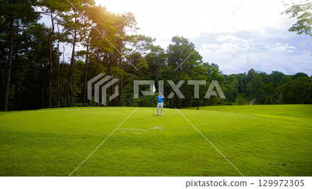 Golfers are putting golf in the evening golf course golf backglound. Golfer hitting golf ball. Golfers are putting golf in the evening golf course golf backglound. Golfer hitting golf ball. 129972305