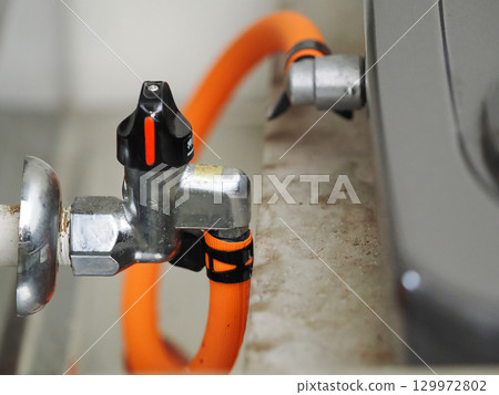 Gas main valve with orange hose connected 129972802