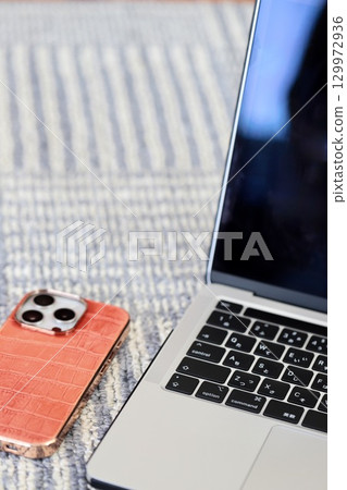 A smartphone placed in front of a laptop keyboard 129972936
