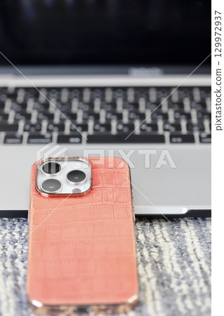 放置在筆記型電腦鍵盤前的智慧型手機 放置在筆記型電腦鍵盤前的智慧型手機 129972937