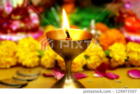 Burning Brass Diya with Flowers in Background Burning Brass Diya with Flowers in Background 129973507