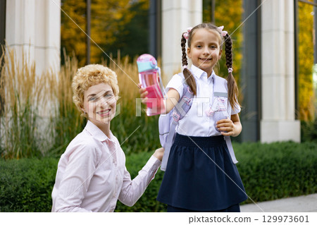 A mother with her daughter at the school, the girl holding a water bottle. A mother with her daughter at the school, the girl holding a water bottle. 129973601