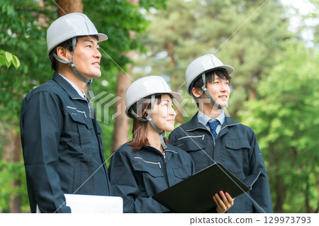 Male and female staff wearing helmets and work clothes at work sites, building sites, and construction sites 129973793