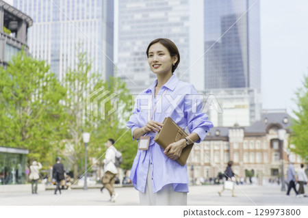 Portrait of a young businesswoman standing with a notebook in an office district Portrait of a young businesswoman standing with a notebook in an office district 129973800