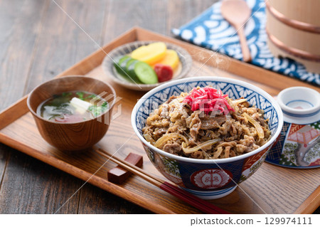 A hot beef bowl set meal and miso soup with pickles on a Japanese table. Image of a traditional Japanese lunch or dinner. 129974111