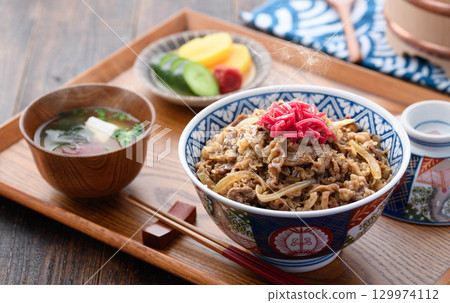 A hot beef bowl set meal and miso soup with pickles on a Japanese table. Image of a traditional Japanese lunch or dinner. 129974112