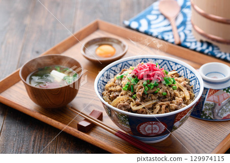A hot beef bowl set meal and miso soup with pickles on a Japanese table. Image of a traditional Japanese lunch or dinner. 129974115