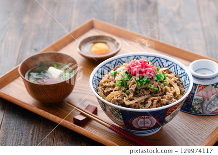 A hot beef bowl set meal and miso soup with pickles on a Japanese table. Image of a traditional Japanese lunch or dinner. 129974117