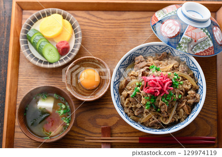 日式餐桌上擺放著熱騰騰的牛肉套餐和加了醃菜的味噌湯。這是一張傳統日式午餐或晚餐的圖片。 日式餐桌上擺放著熱騰騰的牛肉套餐和加了醃菜的味噌湯。這是一張傳統日式午餐或晚餐的圖片。 129974119