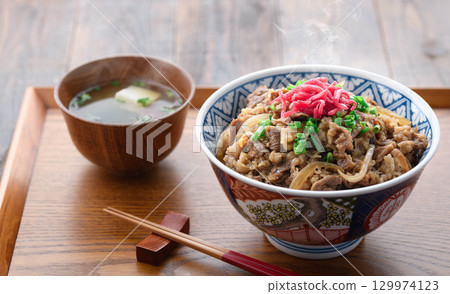 日式餐桌上擺放著熱騰騰的牛肉套餐和加了醃菜的味噌湯。這是一張傳統日式午餐或晚餐的圖片。 129974123