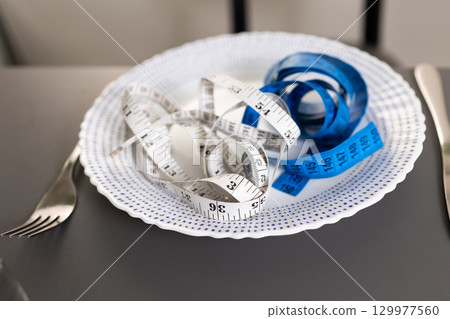 Measuring Tapes in Different Colors Arranged on a Decorative Plate at a Dining Table Measuring Tapes in Different Colors Arranged on a Decorative Plate at a Dining Table 129977560