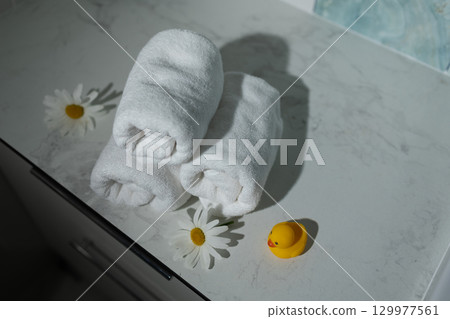 Spa Setting With Rolled Towels, Daisies, and a Rubber Duck on a Marble Surface 129977561