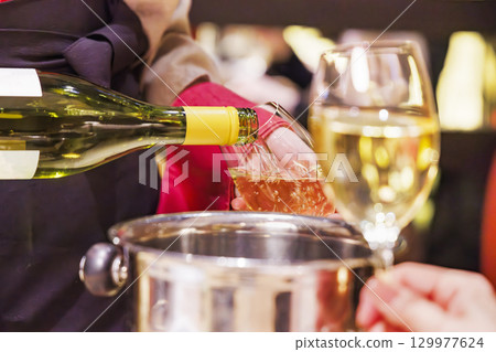A person pouring chilled white wine at a restaurant A person pouring chilled white wine at a restaurant 129977624