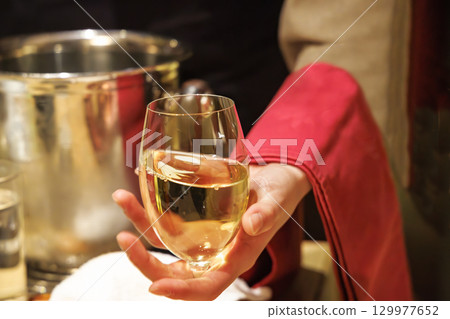 A person pouring chilled white wine at a restaurant 129977652