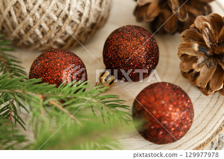 Christmas decorations with red glitter baubles and pine cones on wooden background 129977978