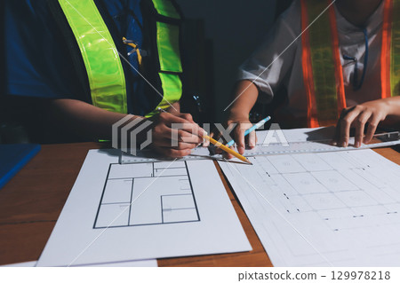 Closeup of team of industrial engineers meeting analyze machinery blueprints consult project on table in manufacturing factory. Working in manufacturing plant or production plant. Closeup of team of industrial engineers meeting analyze machinery blueprints consult project on table in manufacturing factory. Working in manufacturing plant or production plant. 129978218