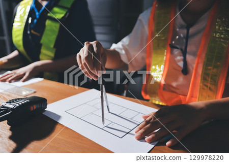 Closeup of team of industrial engineers meeting analyze machinery blueprints consult project on table in manufacturing factory. Working in manufacturing plant or production plant. Closeup of team of industrial engineers meeting analyze machinery blueprints consult project on table in manufacturing factory. Working in manufacturing plant or production plant. 129978220