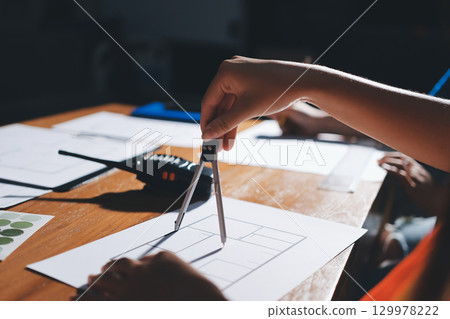 Closeup of team of industrial engineers meeting analyze machinery blueprints consult project on table in manufacturing factory. Working in manufacturing plant or production plant. 129978222