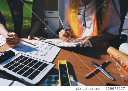 Closeup of team of industrial engineers meeting analyze machinery blueprints consult project on table in manufacturing factory. Working in manufacturing plant or production plant. 129978227