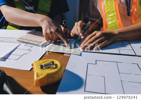 Closeup of team of industrial engineers meeting analyze machinery blueprints consult project on table in manufacturing factory. Working in manufacturing plant or production plant. Closeup of team of industrial engineers meeting analyze machinery blueprints consult project on table in manufacturing factory. Working in manufacturing plant or production plant. 129978241