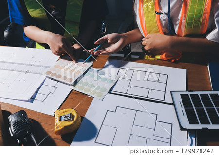 Closeup of team of industrial engineers meeting analyze machinery blueprints consult project on table in manufacturing factory. Working in manufacturing plant or production plant. Closeup of team of industrial engineers meeting analyze machinery blueprints consult project on table in manufacturing factory. Working in manufacturing plant or production plant. 129978242