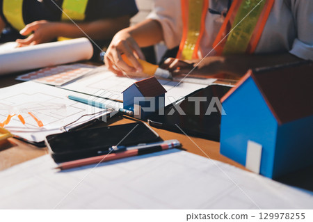 Closeup of team of industrial engineers meeting analyze machinery blueprints consult project on table in manufacturing factory. Working in manufacturing plant or production plant. Closeup of team of industrial engineers meeting analyze machinery blueprints consult project on table in manufacturing factory. Working in manufacturing plant or production plant. 129978255