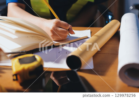 Closeup of team of industrial engineers meeting analyze machinery blueprints consult project on table in manufacturing factory. Working in manufacturing plant or production plant. Closeup of team of industrial engineers meeting analyze machinery blueprints consult project on table in manufacturing factory. Working in manufacturing plant or production plant. 129978256