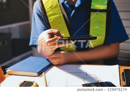Closeup of team of industrial engineers meeting analyze machinery blueprints consult project on table in manufacturing factory. Working in manufacturing plant or production plant. 129978274