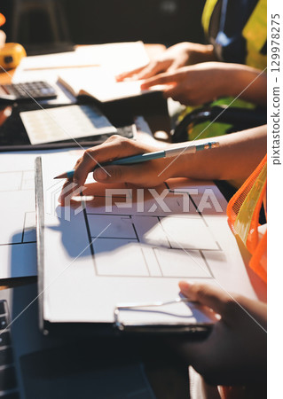 Closeup of team of industrial engineers meeting analyze machinery blueprints consult project on table in manufacturing factory. Working in manufacturing plant or production plant. Closeup of team of industrial engineers meeting analyze machinery blueprints consult project on table in manufacturing factory. Working in manufacturing plant or production plant. 129978275