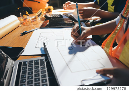 Closeup of team of industrial engineers meeting analyze machinery blueprints consult project on table in manufacturing factory. Working in manufacturing plant or production plant. Closeup of team of industrial engineers meeting analyze machinery blueprints consult project on table in manufacturing factory. Working in manufacturing plant or production plant. 129978276