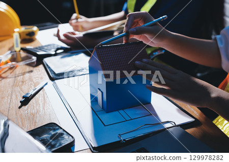 Closeup of team of industrial engineers meeting analyze machinery blueprints consult project on table in manufacturing factory. Working in manufacturing plant or production plant. 129978282