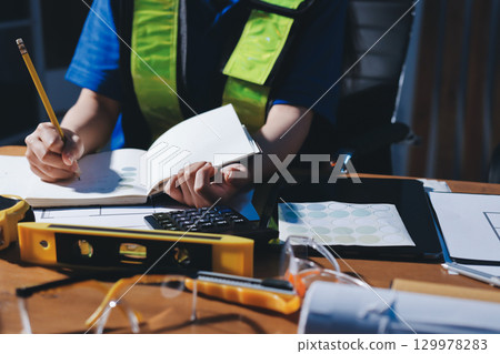 Closeup of team of industrial engineers meeting analyze machinery blueprints consult project on table in manufacturing factory. Working in manufacturing plant or production plant. Closeup of team of industrial engineers meeting analyze machinery blueprints consult project on table in manufacturing factory. Working in manufacturing plant or production plant. 129978283