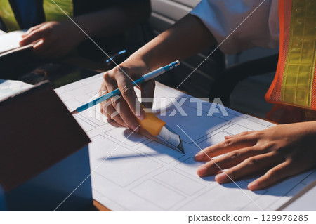 Closeup of team of industrial engineers meeting analyze machinery blueprints consult project on table in manufacturing factory. Working in manufacturing plant or production plant. 129978285