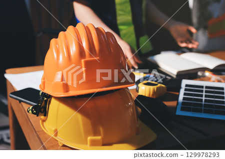 Closeup of team of industrial engineers meeting analyze machinery blueprints consult project on table in manufacturing factory. Working in manufacturing plant or production plant. 129978293