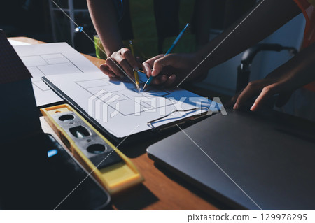 Closeup of team of industrial engineers meeting analyze machinery blueprints consult project on table in manufacturing factory. Working in manufacturing plant or production plant. Closeup of team of industrial engineers meeting analyze machinery blueprints consult project on table in manufacturing factory. Working in manufacturing plant or production plant. 129978295