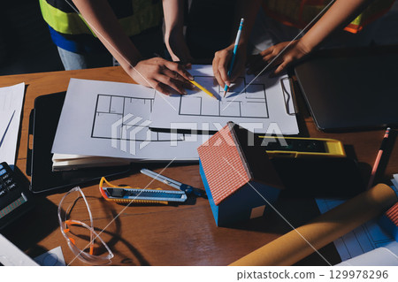 Closeup of team of industrial engineers meeting analyze machinery blueprints consult project on table in manufacturing factory. Working in manufacturing plant or production plant. 129978296