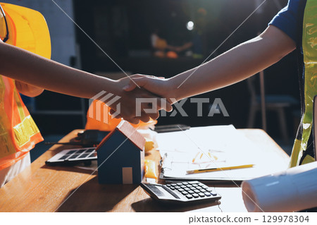 Closeup of team of industrial engineers meeting analyze machinery blueprints consult project on table in manufacturing factory. Working in manufacturing plant or production plant. 129978304