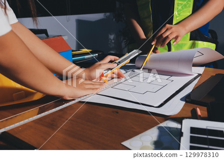 Closeup of team of industrial engineers meeting analyze machinery blueprints consult project on table in manufacturing factory. Working in manufacturing plant or production plant. 129978310