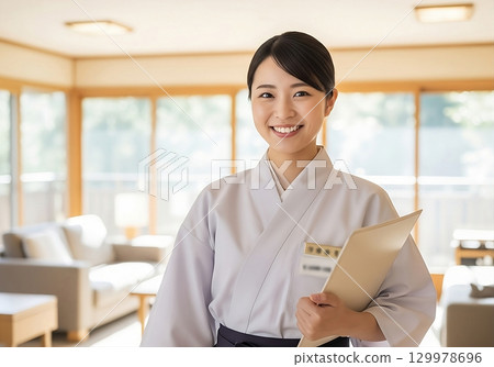 旅館裡一位面帶微笑的女工作人員歡迎客人 旅館裡一位面帶微笑的女工作人員歡迎客人 129978696