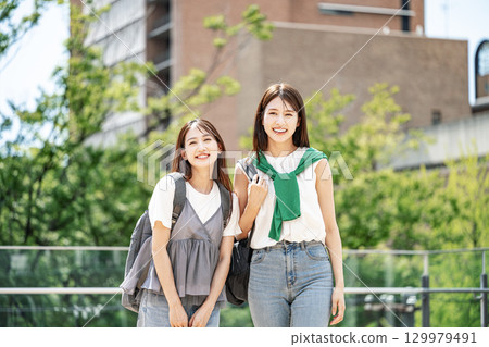 A female college student walking around the campus, chatting happily with her friends 129979491