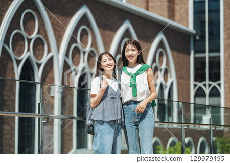 一位女大學生在校園散步，和朋友開心地聊天 129979495