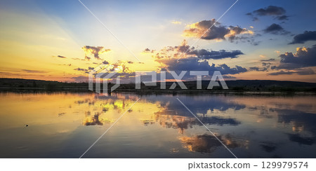 Scenic view of beautiful sunset or sunrise above the pond or lake at spring or early summer evening 129979574