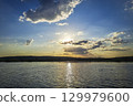 Scenic view of beautiful sunset or sunrise above the pond or lake at spring or early summer evening 129979600
