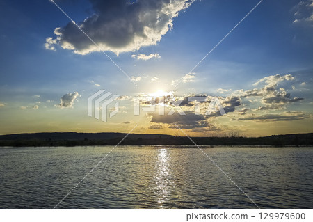 Scenic view of beautiful sunset or sunrise above the pond or lake at spring or early summer evening 129979600
