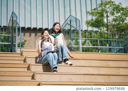 年輕女子與朋友坐在戶外樓梯上 129979686