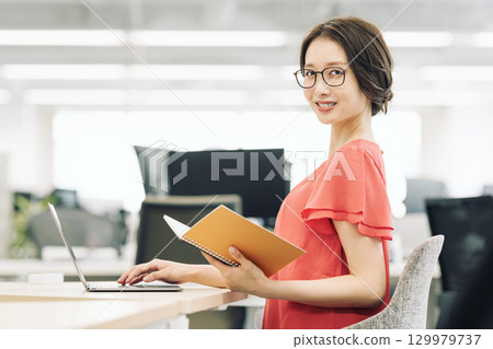 一位職業婦女在辦公室做案頭工作 一位職業婦女在辦公室做案頭工作 129979737