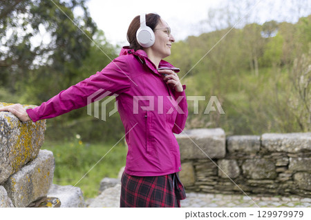 Woman wearing headphones listening to music while hiking in nature 129979979