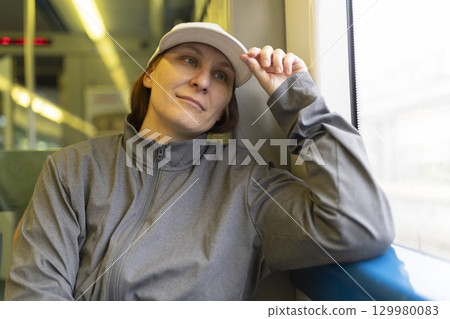 Woman traveling by train, gazing out window, contemplative expression 129980083