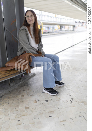 Woman waiting for transportation at train station or bus stop Woman waiting for transportation at train station or bus stop 129980084
